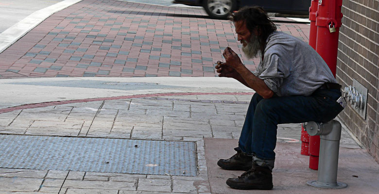 Poverty, a homeless guy sitting on a hydrant.