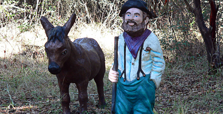 Donkey and man figures in the middle of the woods.